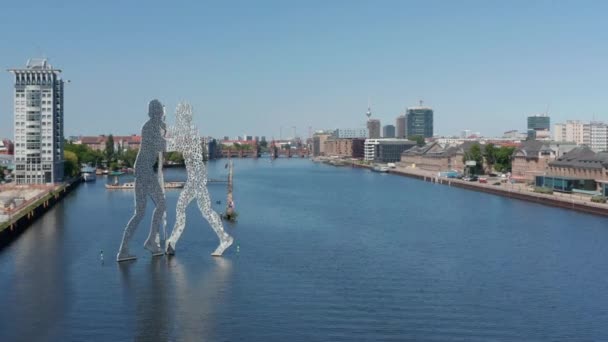 Adelante volar por encima del río Spree alrededor de la escultura Molecule Man. Barcos amarrados en la orilla del río. Día soleado con cielo despejado. Berlín, Alemania — Vídeo de stock