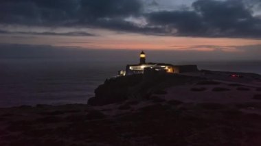 Hava aracının alacakaranlıkta yanıp sönen deniz fenerinde hiper hızı. Ponta da Piedade Deniz Feneri Lagos Algarve, Portekiz 'de, İHA gece lambasına doğru uçuyor.