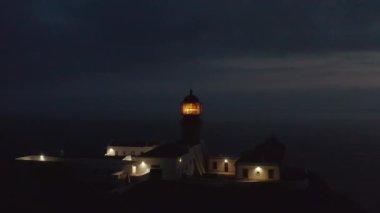 Hava aracı Lagos Algarve, Portekiz, alacakaranlıkta fener fenerinin parlak fresel lenslerine doğru uçuyor.