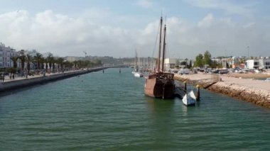 Portekiz ahşap kervanı liman şehri Lagos Algarve 'de demirlemiş. Hava aracı liman kanalında yelkenli tekneye doğru uçuyor.