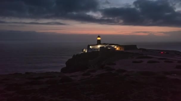 Vzdušný bezpilotní hyperprostorový výpadek blikajícího majáku za soumraku. Ponta da Piedade Lighthouse in Lagos Algarve, Portugal, dron letící směrem k čelní lampě, večer — Stock video