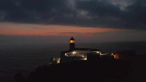 Landschappelijk uitzicht op de prachtige romantische Ponta da Piedade vuurtoren in Lagos Algarve, Portugal, drone naar voren vliegend richting gele fresnel lenskop, avondschemering — Stockvideo