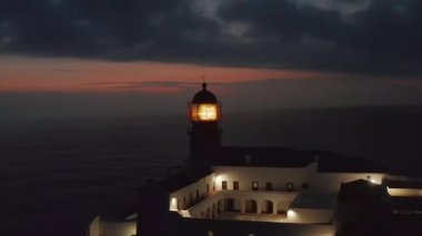 Lagos Algarve, Portekiz 'deki sansasyonel deniz fenerinin etrafında dönen hava, alacakaranlıkta parlayan ışık.