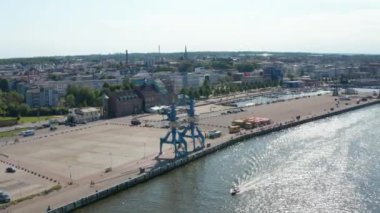 İki liman vinci ile rıhtımın havadan görüntüsü. Nehrin parıldayan su yüzeyi. Arka planda şehir