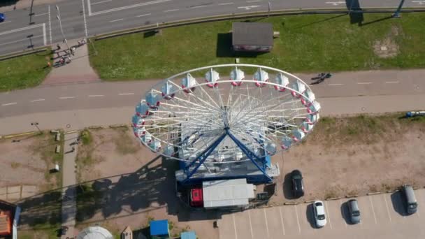 Ferris wheel operating at busy multi lane road. Descending and tilt up reveal of housing estate in city — Stockvideo