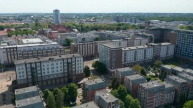 Konut arazisinin üzerinden uçar, aşağı eğilir, tramvay raylarıyla geniş caddeleri gösterir.