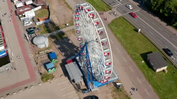 High angle view of rotating Ferris wheel. People enjoying amusement ride in gondolas. Shadow of attraction on ground — Stock videók