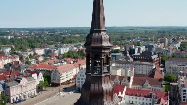 Pan and tilt down footage of church tower and historic city centre with square, gabled houses and city hall in backgrounds — 비디오