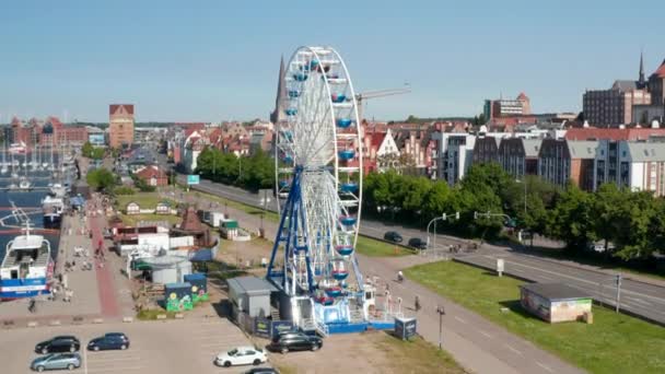Rising view of running Ferris wheel. People enjoying time on attraction. Ascending and tilting down footage with city in background — Stockvideo