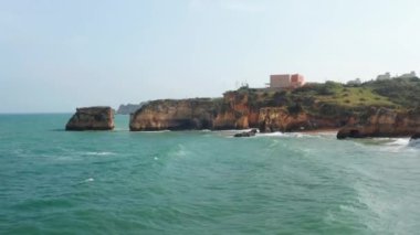 Renkli Lagos uçurumlarına çarpan dalgaların insansız hava aracı görüntüsü, kayalık kıyıların üzerinde ileriye doğru uçan insansız hava aracı inanılmaz bir deniz manzarası ortaya çıkarıyor.