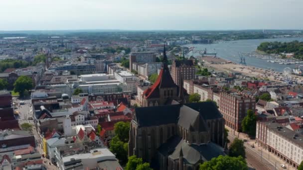 Backwards fly above city. Large brick gothic style religious building of Saint Marys church. Panoramic aerial view of historic city centre — Stockvideo