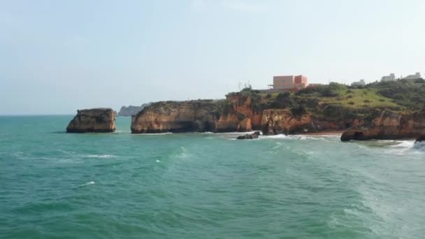 Aerial drone view of waves crashing against colorful Lagos cliff coastline, drone flying foward above rocky coast reveal amazing sea landscape, day — Stock Video