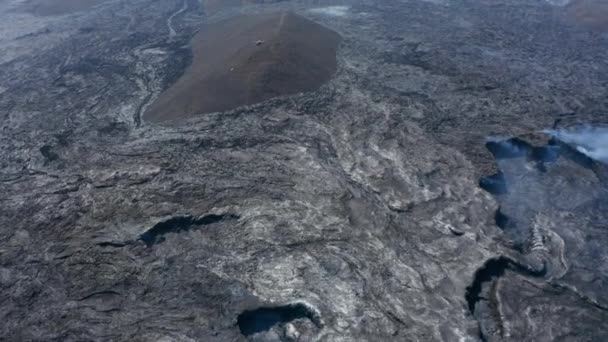 Vasta lava vulcanica nera Fagradalsfjall paesaggio con elicottero in lontananza sopra collina. Veduta aerea drone di incredibile vulcano lava paesaggio fluviale, Islanda, dolly in, giorno — Video Stock