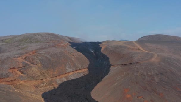 Повітряний безпілотник летить уперед до чорної лави річки Фаградальсфьел, Ісландія, сонячний день. — стокове відео