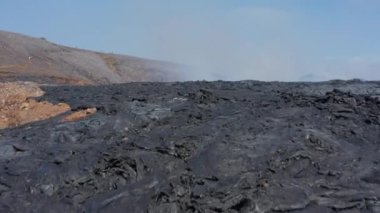 İzlanda Fagradalsfall 'daki diğer dünyaların volkanik manzaraları. Hava aracı siyah dumanlı lavın üzerinde alçaktan uçuyor.