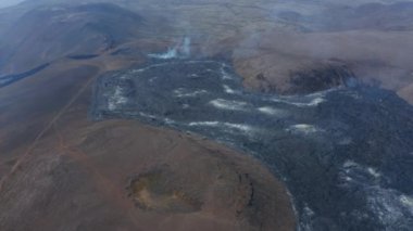 Fagradalsfall, Reykjanes Yarımadası, İzlanda 'da nefes kesici volkanik manzara. Yüksek hava aracı görüntüsü sıcak siyah lavın üzerinde uçuyor, ileri, aşağı, gün içinde