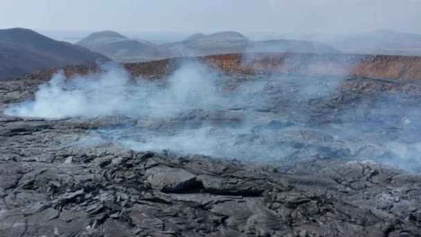 Hava aracı görüntüsü siyah dumanlı lav kraterinin etrafında turistlerin Fagradalsfall volkanını gün boyunca ziyaret etmesiyle dönüyor. — Stok video