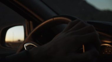 Erkek el direksiyonu tutarken çekilmiş görüntüler. Bir el arabası yolda. Gün batımında düşük ışık sahnesi