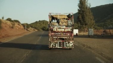 Vahşi Afrika manzarasında ağır kurşunlu yerel bir kamyonun arkasında yol alıyoruz. Tuhaf bir aydınlatma yapan eski arabanın arka görüntüsü. Fas, Afrika