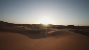 Çöldeki kum tepeciklerini kaydır ve tavaya koy. Doğan güneşe karşı görüş. Aşırı kuru ve çorak arazi. Fas, Afrika