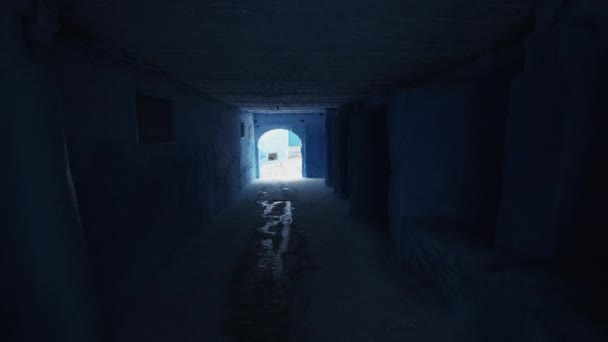 POV-Aufnahmen von Spaziergängen in der Stadt. Blick auf den dunklen Tunnel unter dem Gebäude, der auf einer Treppe in der blauen Stadt Chefchaouen endet. Marokko, Afrika — Stockvideo