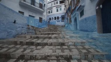 Şef Chaouen 'deki mavi boyanmış evler arasındaki merdivenleri gösteriyor. Düşük açı. Fas, Afrika