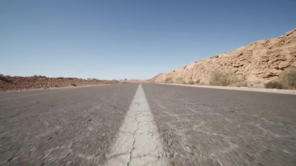 Dopředu nízký let nad osou na asfaltové silnici. Po vodorovných značkách. Suchá a zaprášená krajina s kameny. Maroko, Afrika — Stock video
