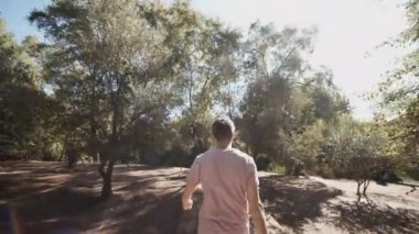 Tahta köprüye doğru ilerleyen adamı takip ediyoruz. Güneş ışığına karşı görüş. Fas, Afrika