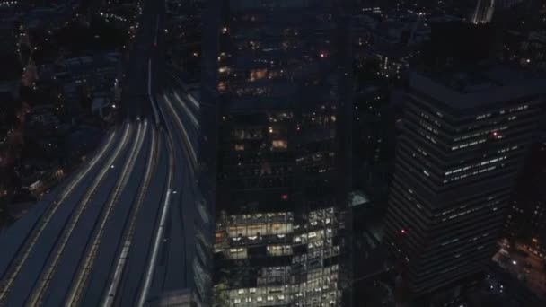 Vista aérea panorâmica da London Bridge Tower, The Shard à noite. Drone inclinar para baixo, circulando em torno do arranha-céu iluminado, inclinar-se revelar espetacular paisagem urbana de Londres — Vídeo de Stock