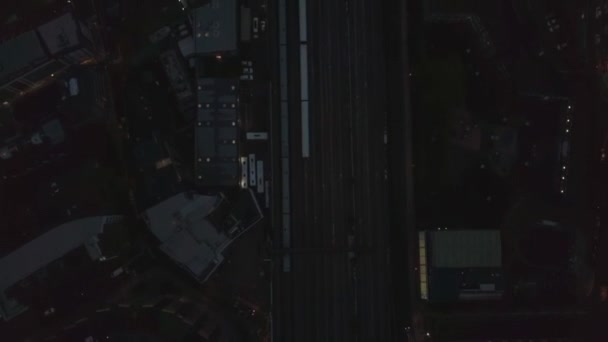Воздушные птицы сверху вниз вид на поезд, проходящий мимо железнодорожного вокзала Лондонского моста в Лондоне, дрон, летящий вперед наклон вверх показывают осколок небоскреба городской пейзаж панорама, вечерняя ночь — стоковое видео