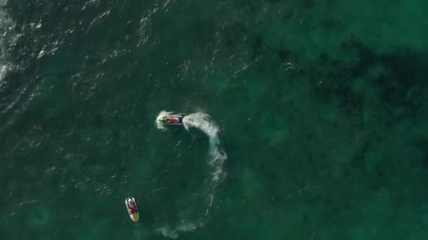 Jet ski cirkelen rond een ander vaartuig. Bovenaanzicht vanuit de lucht. Drone draait boven de Caribische Zee — Stockvideo