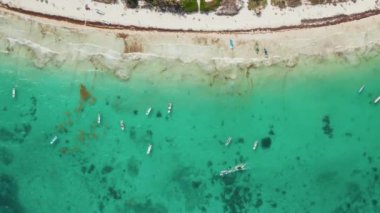 Tulum, Meksika 'da güneşli bir günde hafta sonunun tadını çıkaran, tanınmayan küçük insanlarla dolu, boş ve yelkenli teknelerle dolu yoğun tropikal plajların çekimini yapar.