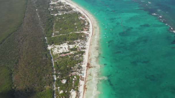 Etablera topp slow motion vy över tom tropisk strand med klart hav i Tulum, Mexiko med en förlängd grönska och skog med en tunn väg — Stockvideo