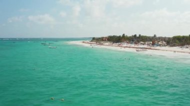 Haftasonu bulutlu bir günde tropikal bir plajda dinlenen ve Meksika 'da Tulum' da yüzmek üzere tekneye binmeye hazırlanan çadırların ve kalabalığın hızlı hareket görüntüsü.