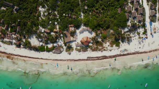 Эстешер сфотографировал оживленный пляж в мексиканском городе Тулум с прозрачным океаном, пустыми лодками и оттаявшей толпой отдыхающих, наслаждающихся и веселящихся в прекрасный день на выходных — стоковое видео