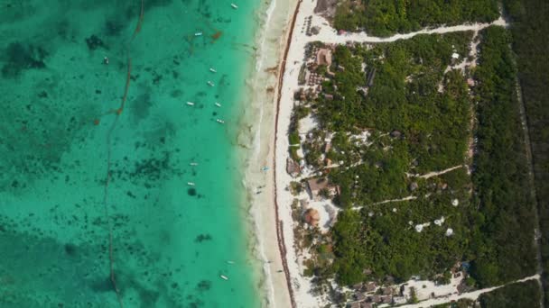 Panorama slow motion vy över tropisk strand med klart hav, tomma båtar och halmtak paraply med människor avkopplande, njuta och ha kul under dagen under helgen i Tulum, Mexiko — Stockvideo
