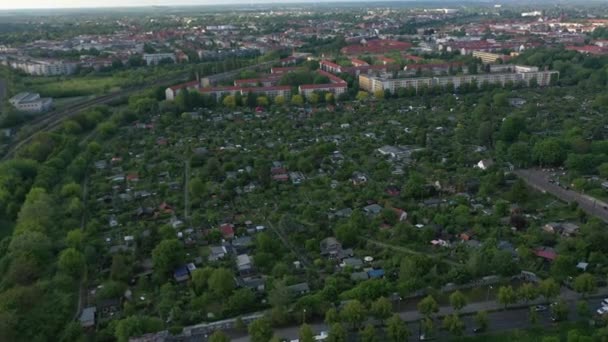 Vlieg boven gemeenschappelijke tuinen omgeven door spoorlijnen en rijen van residentiële gebouwen. Luchtfoto van kleine huisjes in groene vegetatie. Berlijn, Duitsland — Stockvideo