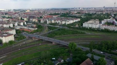 Ön taraflar demiryolu kavşağının üzerinden uçar ve yol köprüsü üzerinden geçer. Şehir merkezindeki panoramik hava manzaralı binalar. Berlin, Almanya