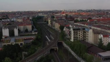 Şehirdeki konut evleri arasında tren raylarında giden bölgesel trenin hava görüntüsü. Berlin, Almanya