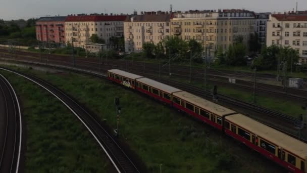 Widok pociągu S bahn przybywającego na stację pod mostem Bosebrucke. Widok z lotu ptaka na wielotorową linię kolejową. Scena miejska w godzinach wieczornych. Berlin, Niemcy — Wideo stockowe