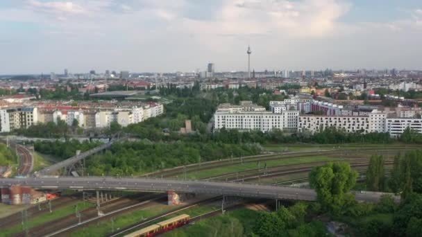 Tył ujawnia wielotorowa linia kolejowa dzieląca się na kierunki, węzeł kolejowy. Panoramiczny widok na miasto z Fernsehturm. Berlin, Niemcy — Wideo stockowe