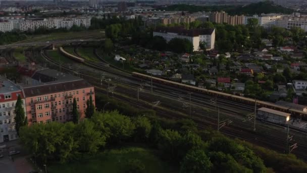 Śledzenie pociągu przejeżdżającego obok innego pociągu. Miejski transport publiczny obsługiwany przez jednostki kolejowe S bahn. Scena miejska oświetlona wieczornym słońcem. Berlin, Niemcy — Wideo stockowe