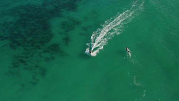 Jong stel jetskiën op hoge snelheid op de groene Caribische Zee. Bovenaanzicht van bovenaf van bovenaf — Stockvideo