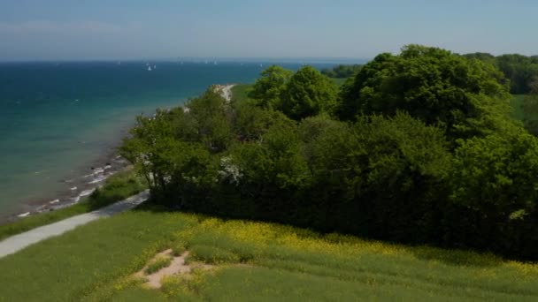 Vue aérienne du paysage paisible du littoral à Brodten, Allemagne, drone tournant autour de la maison rouge face à la mer Baltique, journée ensoleillée — Video