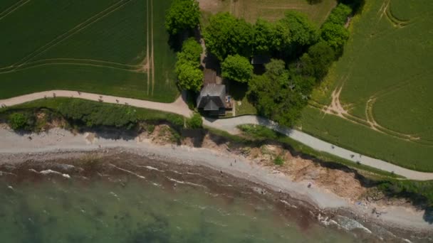 Oiseaux aériens vue aérienne du haut vers le bas du littoral de Brodten Beach avec sentier de promenade près du rivage et de la maison près d'un vaste champ vert, jour — Video