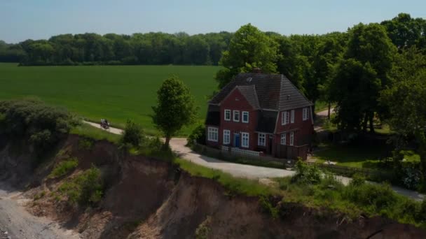 Luchtfoto drone cirkelen rond prachtige houten rode huis met uitzicht op de Oostzee in Brodten, Duitsland, drone vliegen achteruit onthullen majestueuze kustlijn landschap, dag — Stockvideo