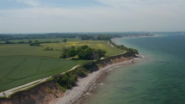 Cirkel pan antenne drone uitzicht op kustlijn strand met uitgestrekt groen veld in Brodten, Duitsland op rustige lentedag — Stockvideo