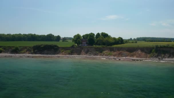 Belle vue aérienne de la mer Baltique côte d'eau turquoise, drone volant vers l'avant vers la maison rouge face à la mer, inclinaison vers le bas à l'oeil des oiseaux vue du haut vers le bas, jour — Video