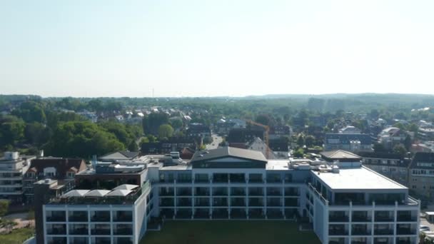 Drone aérien volant vers l'avant au-dessus de l'hôtel de villégiature et abrite des rues de bâtiments à Scharbeutz, Allemagne, jour — Video