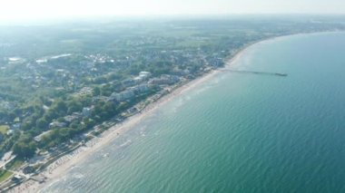 Baltık deniz insansız hava aracı manzarası, Scharbeutz, Almanya 'da yaz mevsiminde turist plajı, gün boyu kıyıya doğru eğiliyor.
